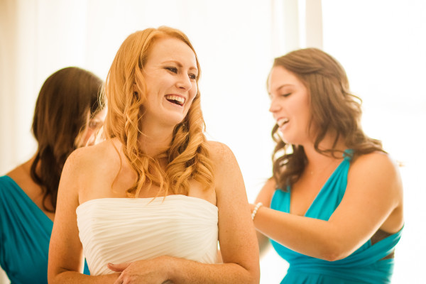 Putting on dress with help of bridesmaids